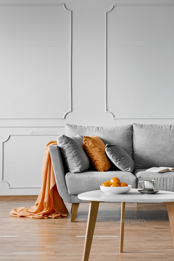 Silver grey and orange pillows on scandinavian sofa copy space